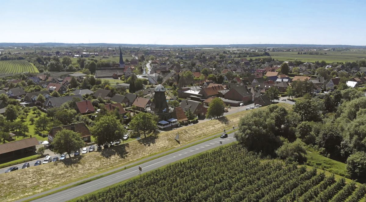 Drohenaufnahme vom Borsteler Ortskern. Im Vordergrund Alter Elbdeich mit der Galerie-Holländer Windmühle, im Hintergrund die Kirche