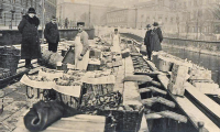 Schwarz-Weiß-Foto um 1930 eines Altländer Obsthändlers auf seinem Kahn in Berlin. Kunden betrachten das Obst, das in Siften angeboten wird.